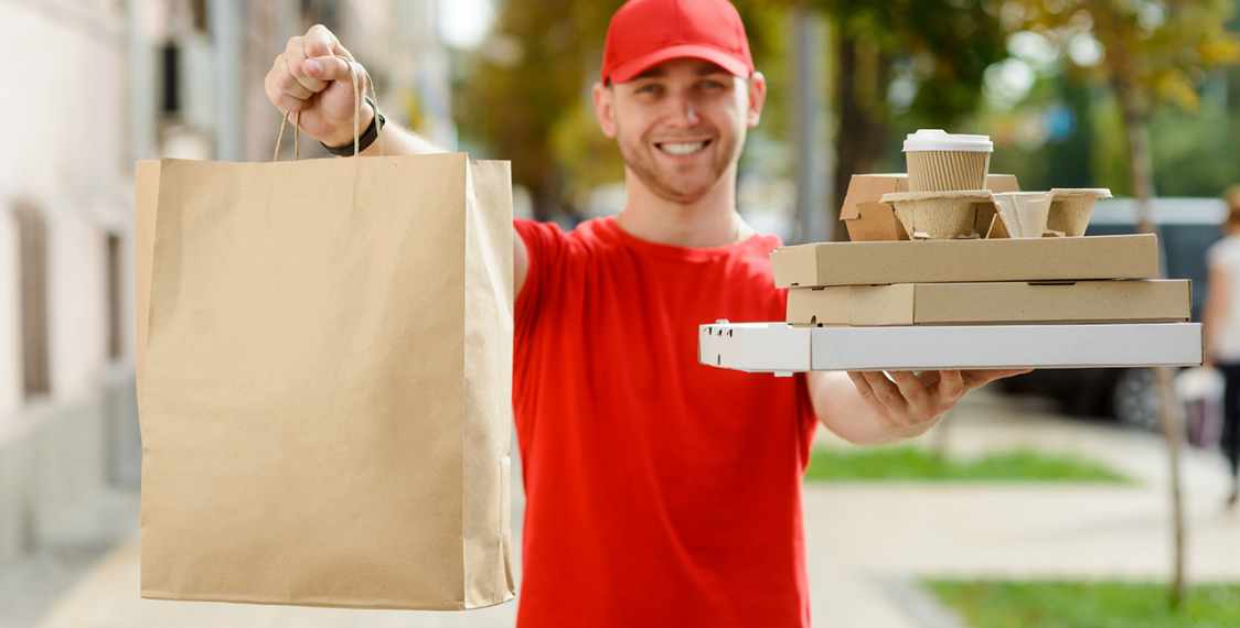 Um entregador sorridente segurando uma caixa, representando a eficiência e a satisfação do fast delivery no comércio moderno.